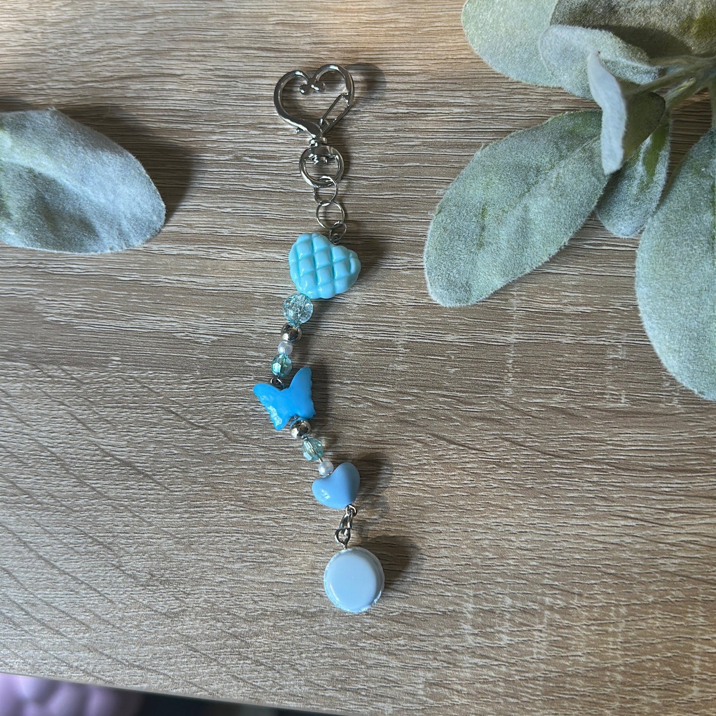 Decorative keychain with blue beads on a wooden surface