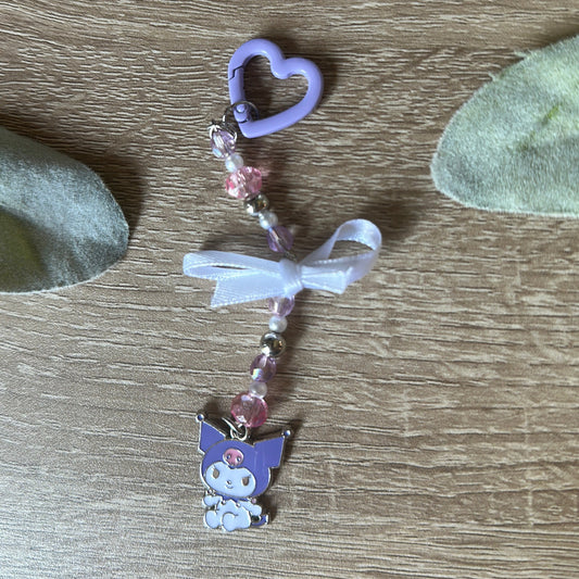 Heart-shaped keychain with cartoon character on a wooden surface