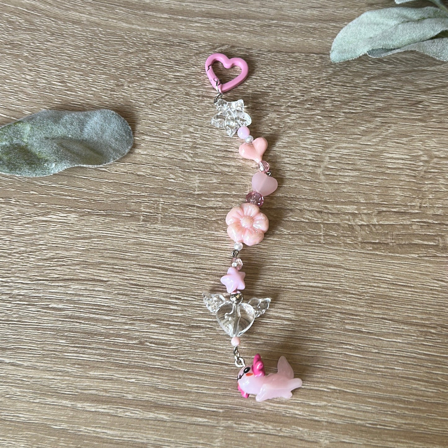 axolotl keychain with pink. beads on wooden surface