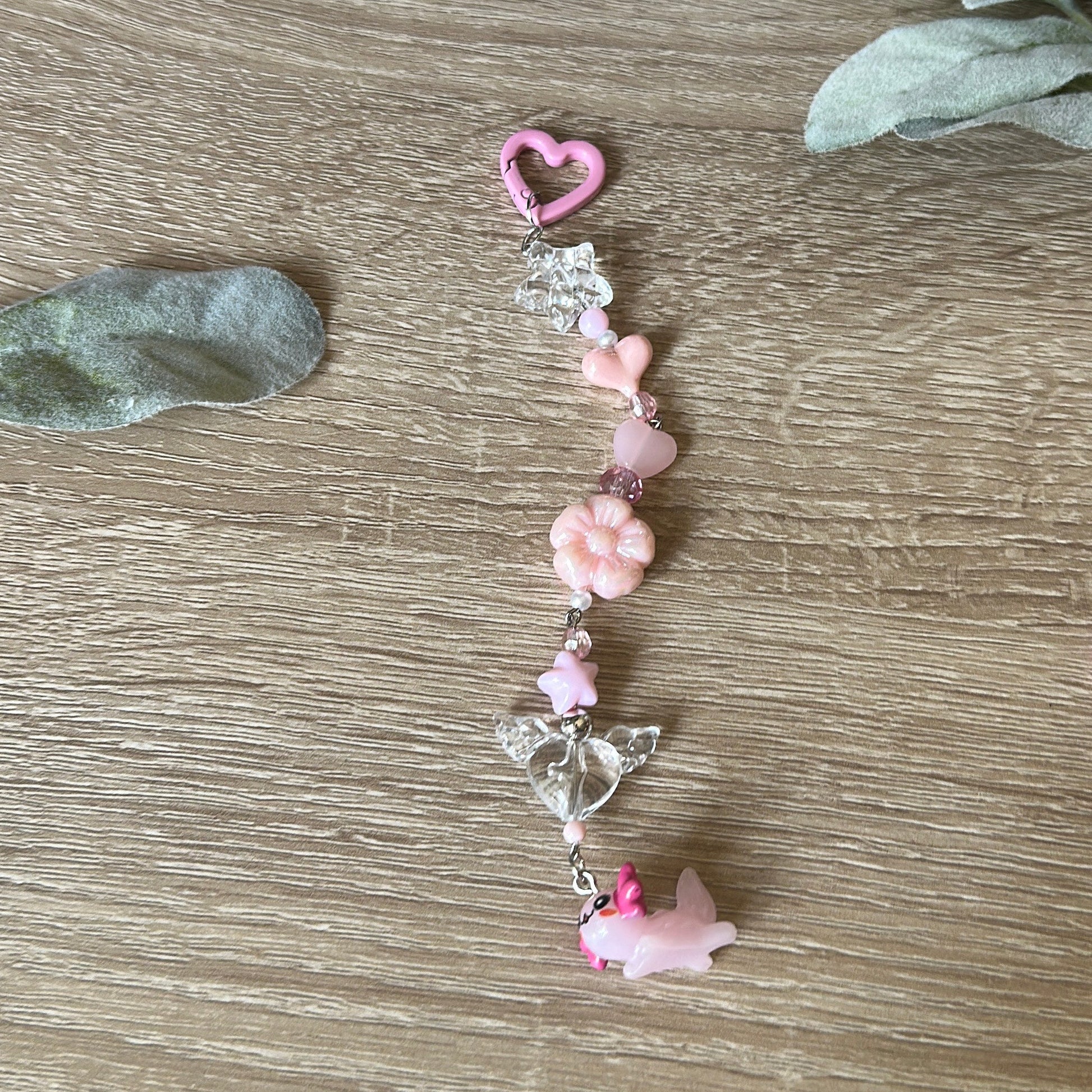 axolotl keychain with pink. beads on wooden surface